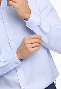  Lichtblauw overhemd met button-down kraag, plastic knopen, lange mouwen en gladde stof. Close-up van de manchet detail en pols.