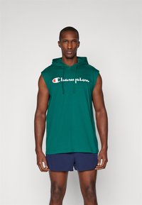 Zelená bezrukávová mikina vyrobená z bavlny, s tkaničkou a bílým logem "Champion" přes hruď. Jednoduchý design, pohodlný střih.