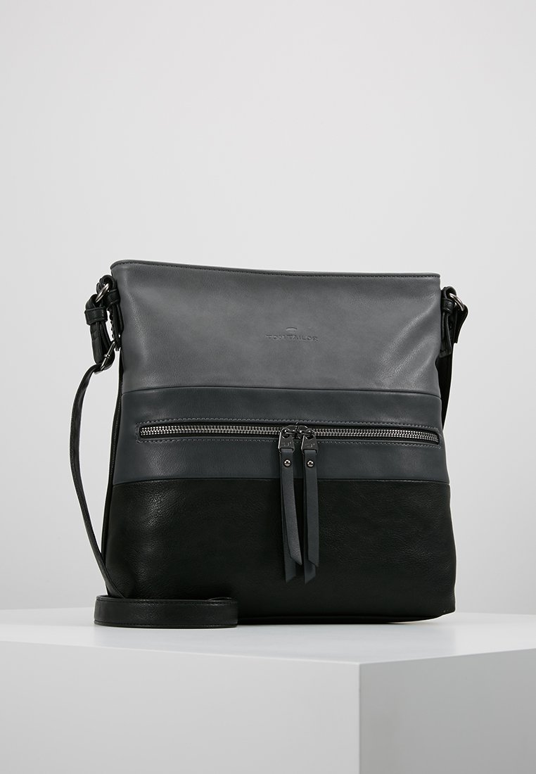 Bolso de cuero cruzado en gris y negro. Cuenta con un bolsillo frontal con cremallera, dos anillas para la cremallera y una correa ajustable. Acabados lisos y texturizados.