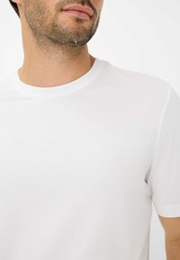 T-shirt bianco a girocollo realizzato in morbido cotone, con maniche corte, caratterizzato da un design semplice e senza motivi o dettagli visibili.