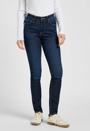 Jean en denim bleu foncé avec une taille haute, coupe slim et coutures dorées. Comprend une fermeture à bouton et zip à l'avant, avec un design classique à cinq poches.