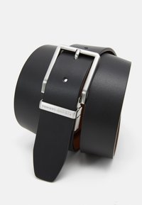 Cintura in pelle nera con una fibbia in metallo argentato. Presenta una texture liscia, fori regolabili e un accento con logo sulla fibbia.