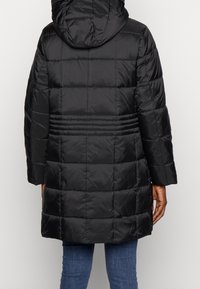 Abrigo de plumas negro con capucha, que presenta secciones acolchadas y mangas amplias. Material suave y brillante con detalles de costura horizontal.