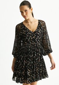 Black dress with a V-neck, sheer long sleeves, and a tiered skirt. Features multicolored floral patterns and a light, textured fabric.