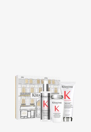 Set per la cura dei capelli Kérastase con una bottiglia spray argentata, un barattolo bianco e un tubetto bianco, con dettagli dorati e rossi sulla confezione.