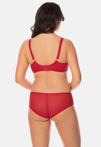 Ensemble de lingerie rouge comprenant un soutien-gorge lisse avec des bretelles réglables et un dos en mesh, associé à une culotte transparente assortie.