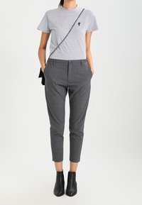 Grå kortärmad t-shirt med en liten kaktusbrodyr, matchad med skräddarsydda grå byxor och svarta ankelstövlar. Enkelt design och neutrala färger.