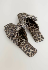 Čevlji za enostavno obuvanje s leopardjo maso in obliko kvadratnega prsta ter tkaninsko pentljo na zgornjem delu. Imajo ravno podplat in gladko teksturo.