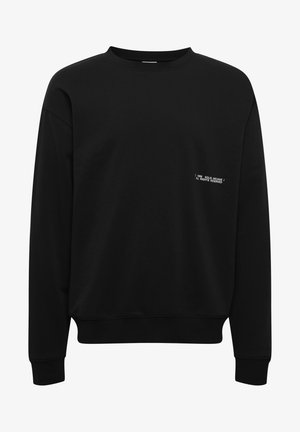 Musthave musta dressipluus, millel on ümar kaelus, pikad varrukad ja soonikkant. Ees on valge tekst, mis ütleb "1999 SOLID ARCHIVE / KÕIK ÕIGUSED KAITSTUD."