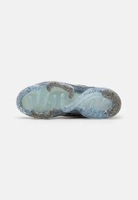 Shoe sole featuring a translucent blue material with a textured surface and grey accents. Unique curvy design with embedded sparkles.