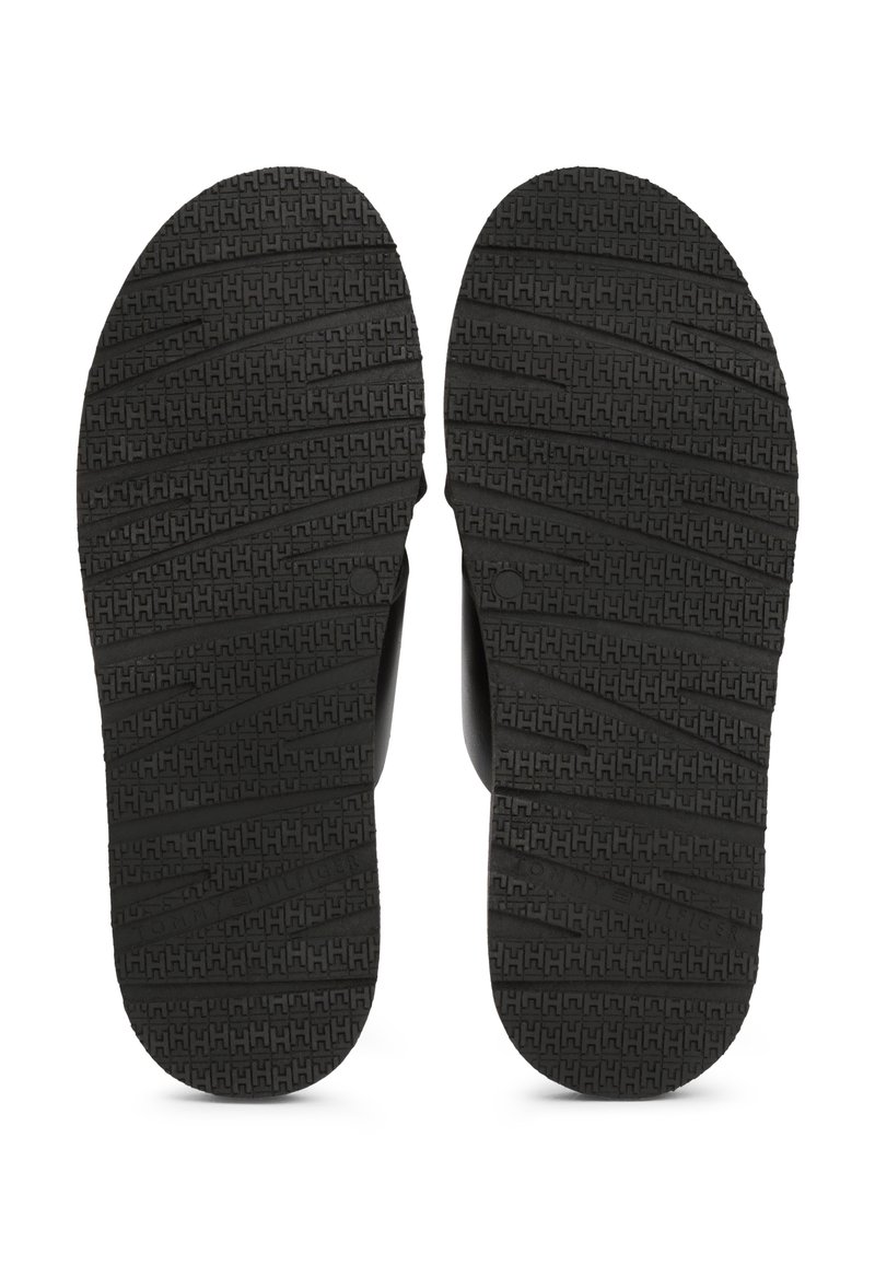 Chanclas de goma negra con suelas texturizadas, que presentan un patrón en zigzag para mayor agarre y bordes suaves, diseñadas para la comodidad y la durabilidad.