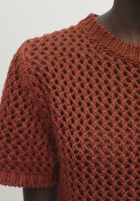 Maglione corto a maniche corte di colore rosso ruggine lavorato a maglia, con un ampio scollo e un design a rete aperta con finitura testurizzata.