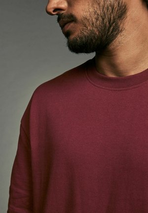 T-shirt crew à col ras du cou de couleur marron, fabriqué en tissu doux et texturé avec une coupe décontractée, mettant en valeur le détail de l'encolure et la couture de l'épaule.