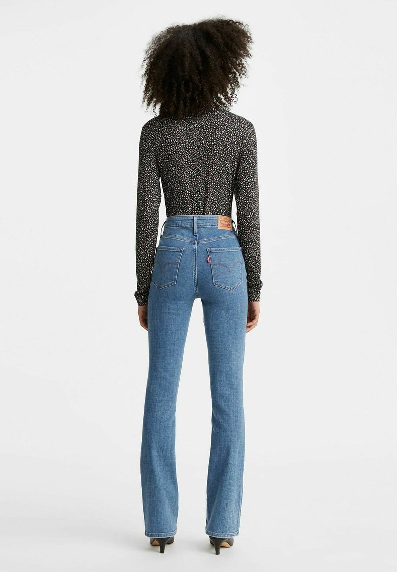 Jeans de tiro alto en azul con una silueta ajustada, que muestran un diseño clásico de cinco bolsillos y sutiles detalles de costura.