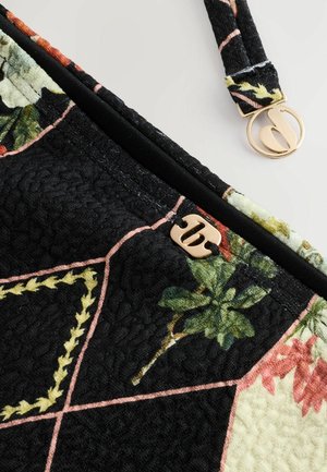 Gestepptete schwarze Tasche mit floralen Mustern, ausgestattet mit einem goldenen Reißverschluss und Beschlägen sowie kontrastierenden Farbbereichen, die in Pink umrandet sind.