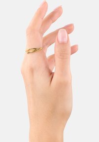 Anillo de oro retorcido en una mano, con un acabado suave y un diseño entrelazado. Los dedos tienen una manicura natural, mostrando un aspecto neutro.