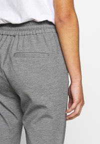 Grijze trainingsbroek met een elastische tailleband, voorzien van een achterzak met een gestikte opening, zachte textuur en een relaxte pasvorm.