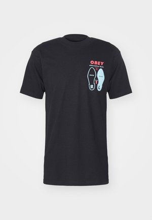 Sort bomulds-t-shirt med korte ærmer, med et grafisk print af skosilhuetter og "OBEY" i røde og blå accenter.