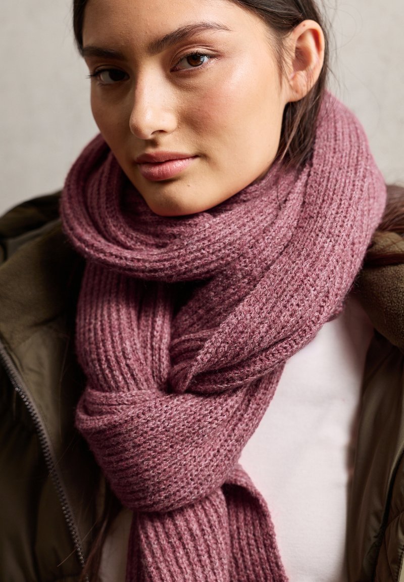 Gebreide sjaal met een zachte, geribbelde textuur in een gedempt mauve kleur. Losjes gewikkeld, is het gemaakt van dik garen, dat warmte en comfort biedt.