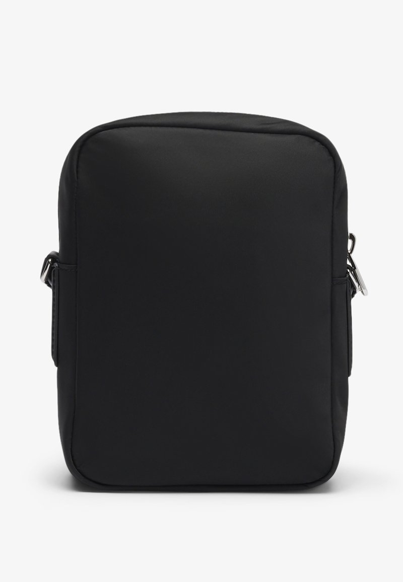 Sac à dos en nylon noir de forme rectangulaire, doté d'une fermeture éclair, d'une sangle ajustable et d'une texture lisse et mate.