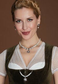 Grünes Samtkleid mit Spitzenakzenten, über einer weißen Bluse geschichtet. Perlen- und Silber-Schmuck beinhaltet einen Sternanhänger und passende Ohrringe.