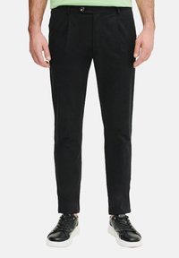 Czarne dopasowane spodnie o slim fit, z plisowanym wzorem i gładką bawełnianą teksturą, w połączeniu z czarnymi sneakersami z białymi podeszwami.