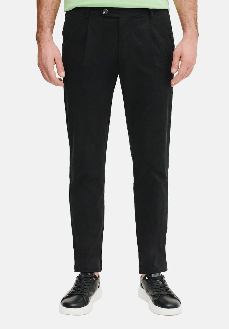 Czarne dopasowane spodnie o slim fit, z plisowanym wzorem i gładką bawełnianą teksturą, w połączeniu z czarnymi sneakersami z białymi podeszwami.