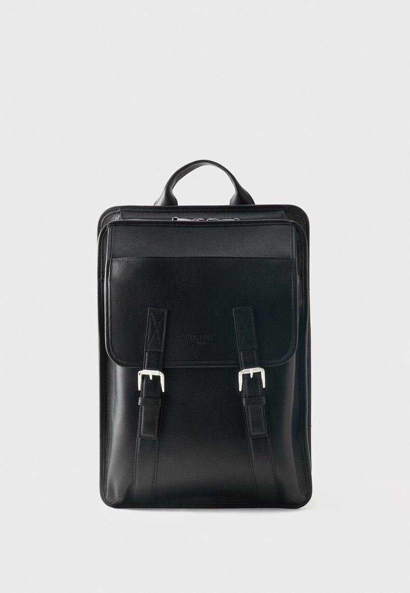 Sort læderrygsæk med topgreb, frontlomme med klap sikret med to sølvspænder og lynlås i toppen.