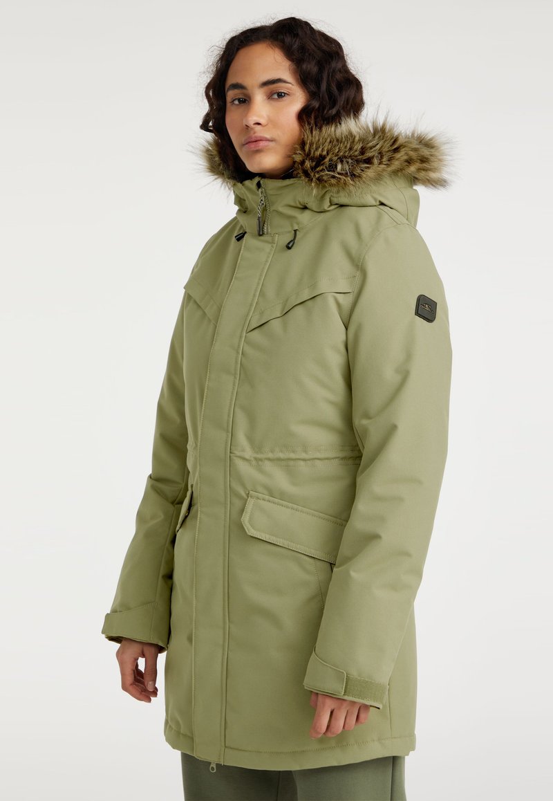 Groene parka met een bontgevoerd capuchon, ritssluiting, twee voorzakken en een waterafstotende stof. Voorzien van verstelbare manchetten.