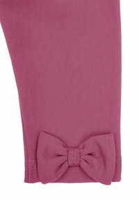 Spodnie wykonane z miękkiego, teksturowanego różowego materiału z dekoracyjną kokardą przy mankiecie, podkreślające dopasowany krój i schludne wykończenie.