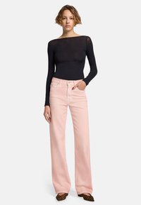 Top nero a maniche lunghe abbinato a jeans a gamba larga rosa chiaro. I jeans presentano una vita alta e un design classico a cinque tasche.