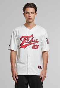 Maillot de baseball blanc avec des accents rouges, design à rayures, devant à boutons et un grand graphique "TUBU 05". Présente un logo sur la manche et une texture textile.