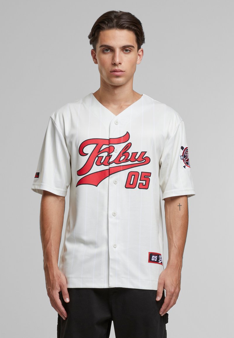 Maillot de baseball blanc avec des accents rouges, design à rayures, devant à boutons et un grand graphique "TUBU 05". Présente un logo sur la manche et une texture textile.