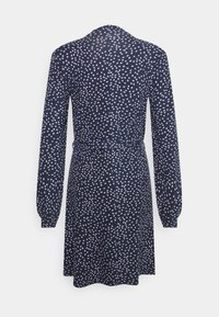 Marinblå klänning med långa ärmar, bälte vid midjan och ett vitt och rosa prickmönster. Knälång design och slät tygtextur.