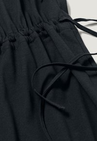 Schwarzer, weicher Stoff mit einem gerafften elastischen Bund und Kordeln. Verfügt über eine glatte Textur und dezente Nähte. Verstellbare Passform.