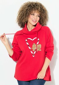 Pullover rosso con collo a cowl, caratterizzato da un design a forma di cuore e fiocco in paillettes oro e bianche. Realizzato in materiale morbido, con maniche lunghe e spacco laterale.