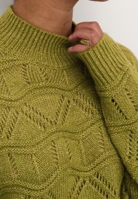 Gestrickter Pullover in Olivgrün mit strukturiertem, gemustertem Design mit Zickzackformen und Lochstrickdetails. Gerippter Kragen und Bündchen.