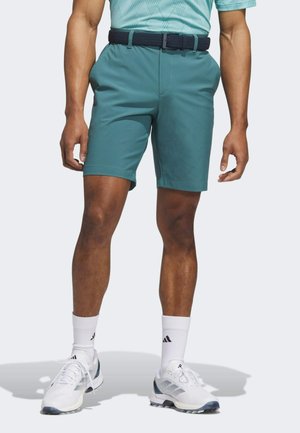 Pantaloni corti turchesi con finitura testurizzata, vita elasticizzata e tasche. Abbinati a scarpe da ginnastica bianche e calzini bianchi a coste.