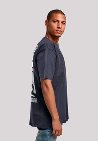 Dark blue cotton t-shirt with short sleeves, featuring a large white graphic print on the back. Relaxed fit, crew neckline, and soft texture.