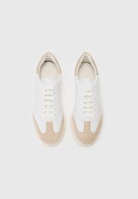 Weiße Sneakers mit einem Obermaterial aus glattem Leder und beigen Wildlederakzenten, runder Zehenform und Schnürdesign. Dezente Perforationen an den Seiten.