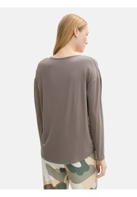 Lange mouwen, losse top in een gedempt taupe-kleur, met een ronde hals en een gladde textuur, gecombineerd met camouflage-patroon broeken.