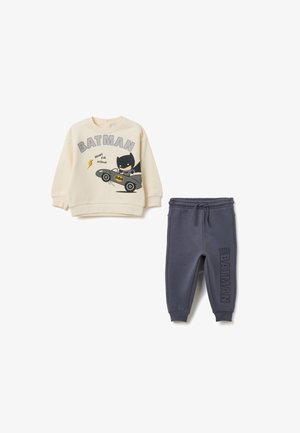 Sweatshirt beige pour enfants avec un graphique de Batman, comprenant une voiture et du texte. Pantalons de survêtement gris foncé avec l'inscription "THE BATMAN" le long de la jambe. Mélange de coton confortable.