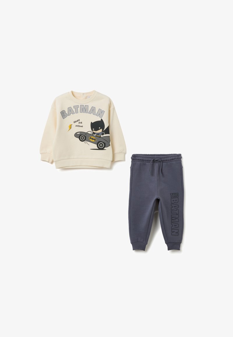 Beige Sweatshirt für Kinder mit Batman-Grafik, die ein Auto und Text zeigt. Dunkelgraue Sweatpants mit dem Aufdruck "THE BATMAN" entlang des Beins. Bequemer Baumwoll-Mix.