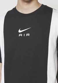 Schwarzes und weißes T-Shirt mit kurzen Ärmeln aus Baumwolle, mit Rundhalsausschnitt, zentralem "Nike"-Logo und dem Text "AIR".