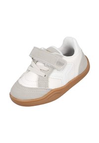 Zapatilla blanca con detalles en gris claro, con una correa de Velcro, punta redondeada, materiales texturizados y suela de goma color canela.