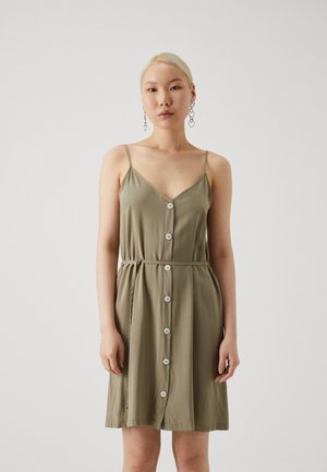 Olivengrünes Kleid mit dünnen Trägern, V-Ausschnitt und einer Knopfleiste an der Vorderseite. Mit einem Kordelzug in der Taille und einem knielangen Rock.