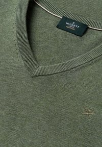 Maglione verde oliva con scollo a V, collo a coste, piccolo logo ricamato sul petto e etichetta nera Hackett London Heritage all'interno del collo.