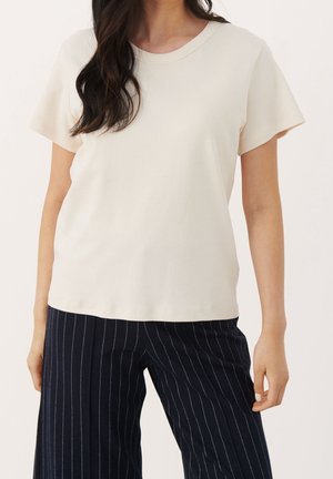 Cream-colored short-sleeve t-shirt with a round neckline, made of soft fabric, paired with navy pinstripe wide-leg pants.
