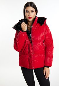 Rød pufferjakke med en blank sort hætte, lynlås og trykknaplukning samt sidelommer, der har en quilted tekstur og fitted manchetter.