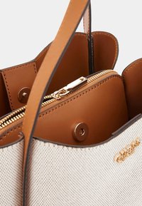 Beige handbag with brown accents, featuring a zippered compartment, gold-tone hardware, and a textured exterior. Main opening with snap closure.